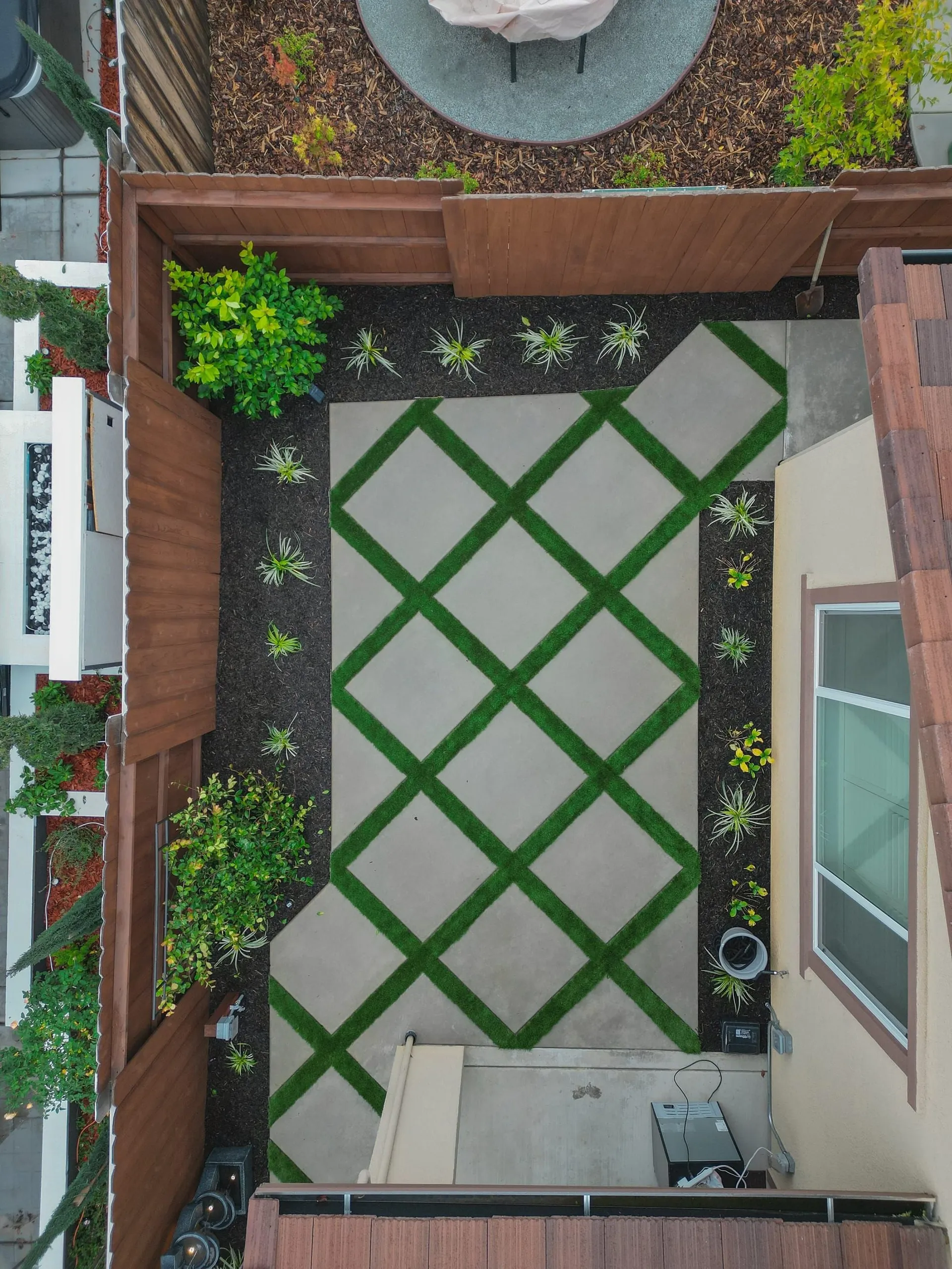Overhead view of a diamond-pattern paver patio with turf bands in Sacramento