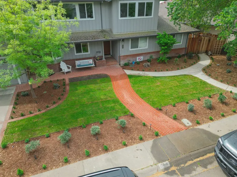 Aerial view of front yard with brick walkway, fresh sod, and new plantings in Sacramento