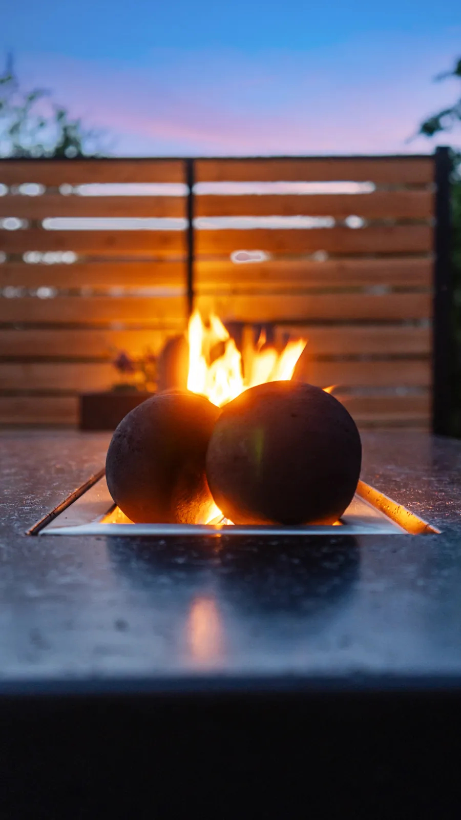 Gas fire bowls burning on a fire table at dusk in a Sacramento backyard
