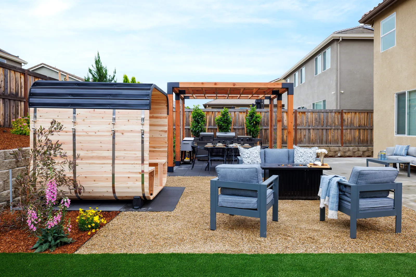 Barrel sauna, fire table lounge, and cedar and steel pergola in a new backyard by Stuteville Landscaping