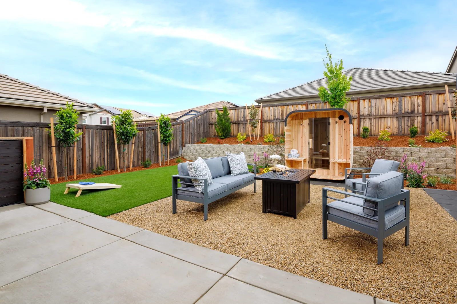 Gas fire table and lounge seating on pea gravel next to the turf lawn