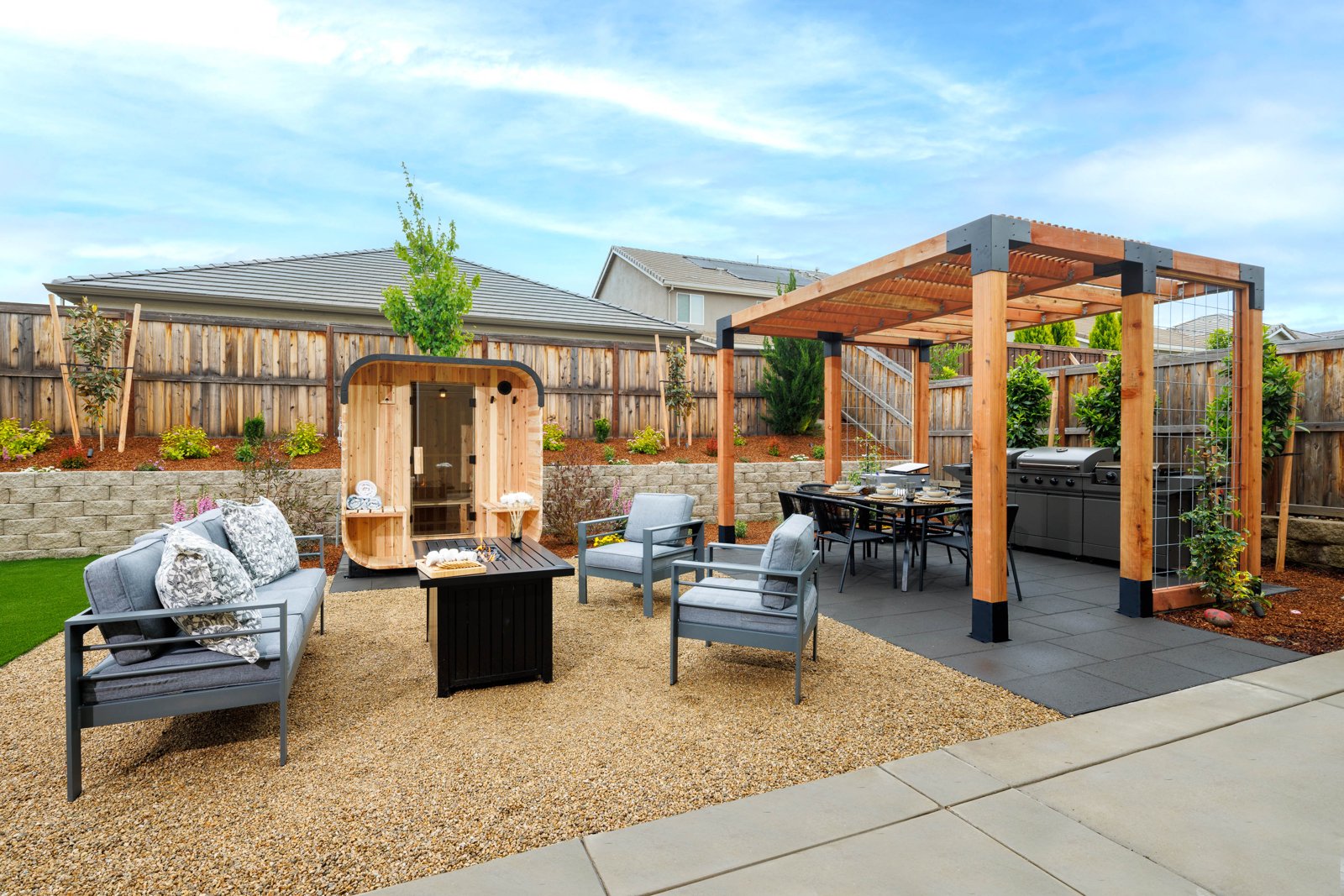 Backyard with cedar and steel pergola, outdoor kitchen, barrel sauna, and fire table lounge by Stuteville Landscaping