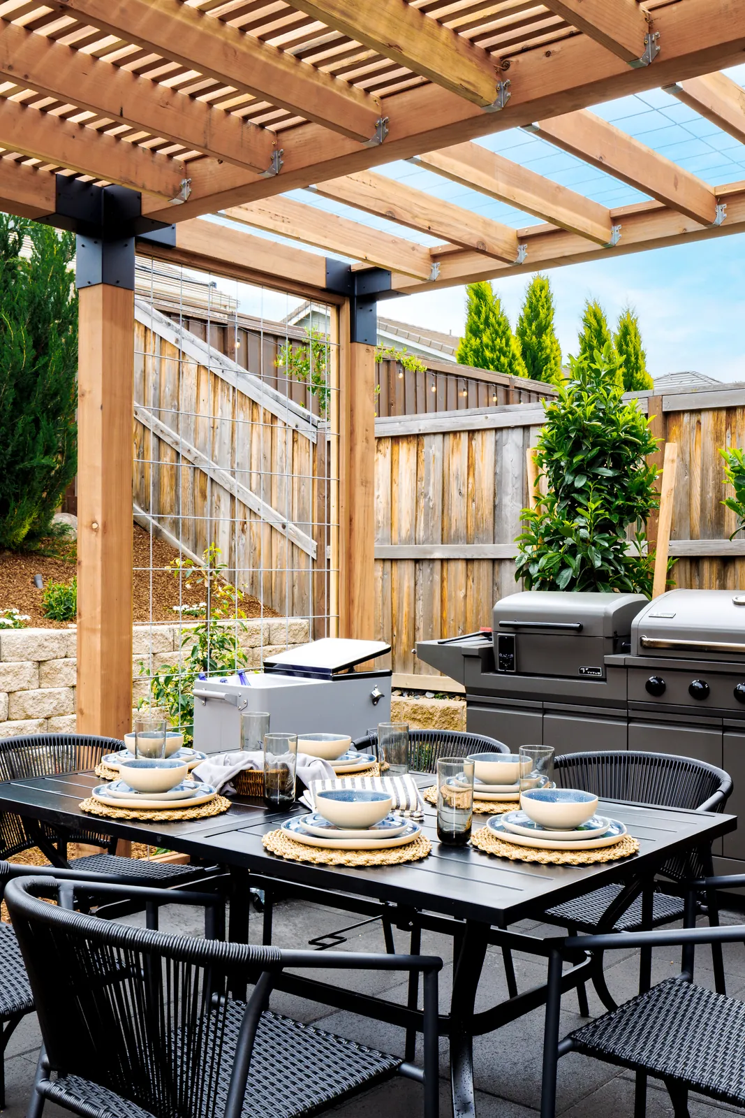 Set dining table under the pergola beside the outdoor kitchen