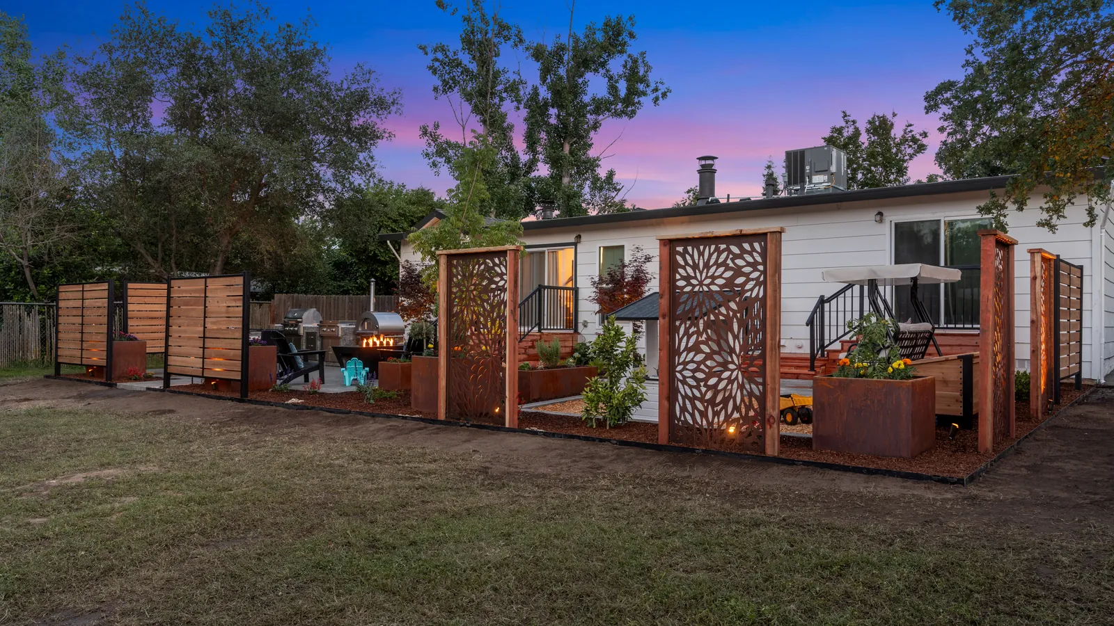 After: the back of the house at dusk with lit corten and cedar screens and planters