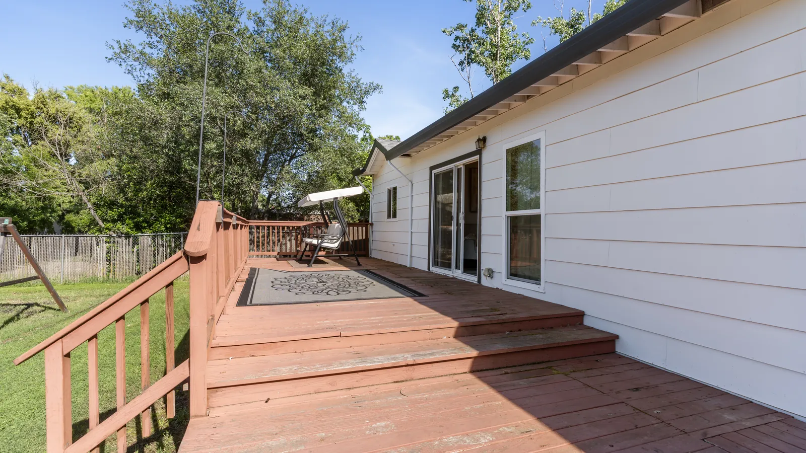 Before: an older raised wood deck with wood railings along the house