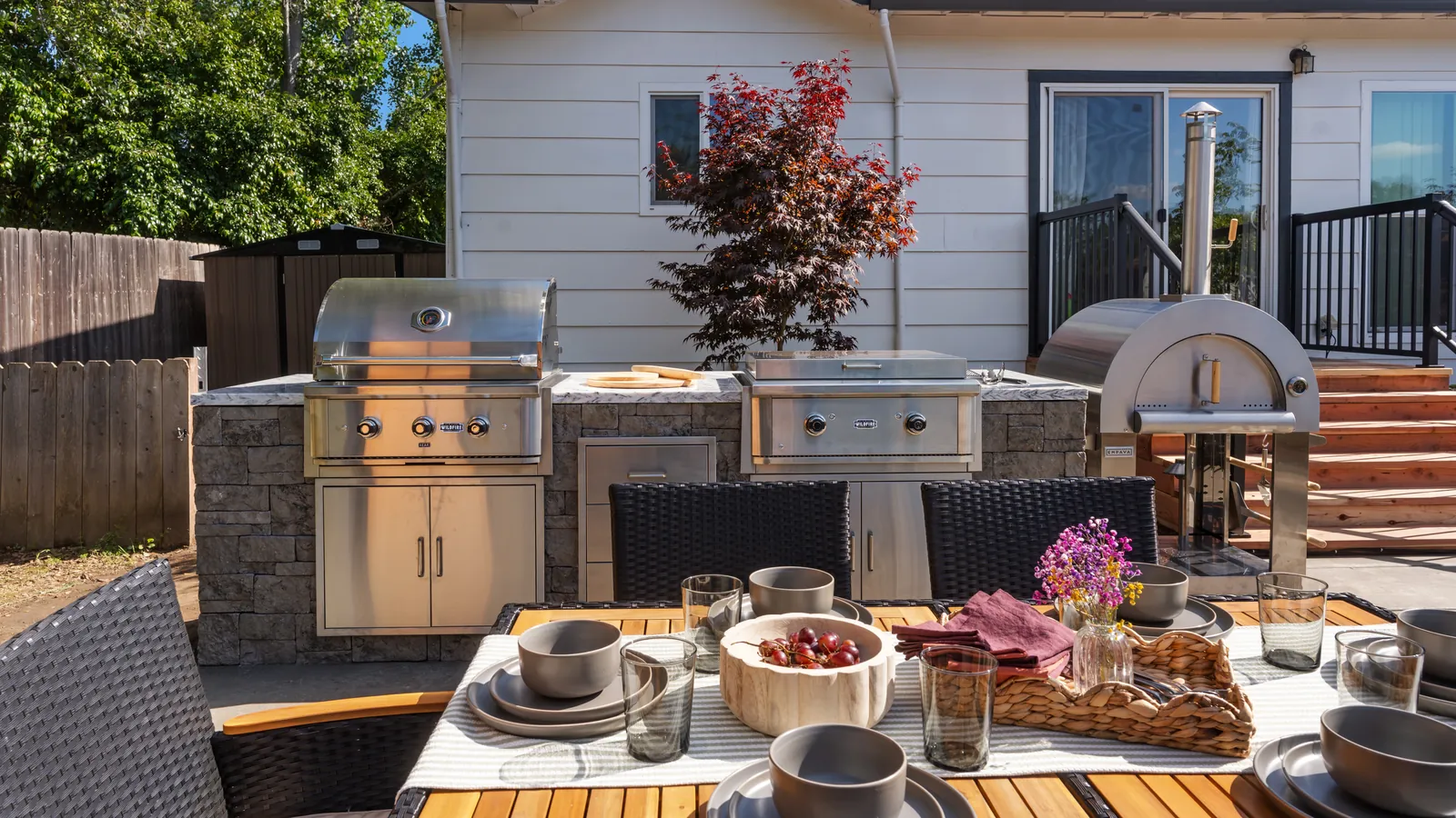 Outdoor kitchen with stone veneer counter, built-in grills, and pizza oven