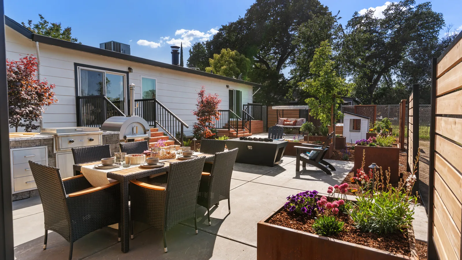 Daytime view of the patio, outdoor kitchen, and corten planters behind the house