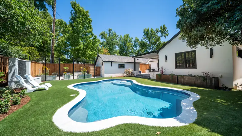 Finished backyard with a freeform pool, turf lawn, and plantings