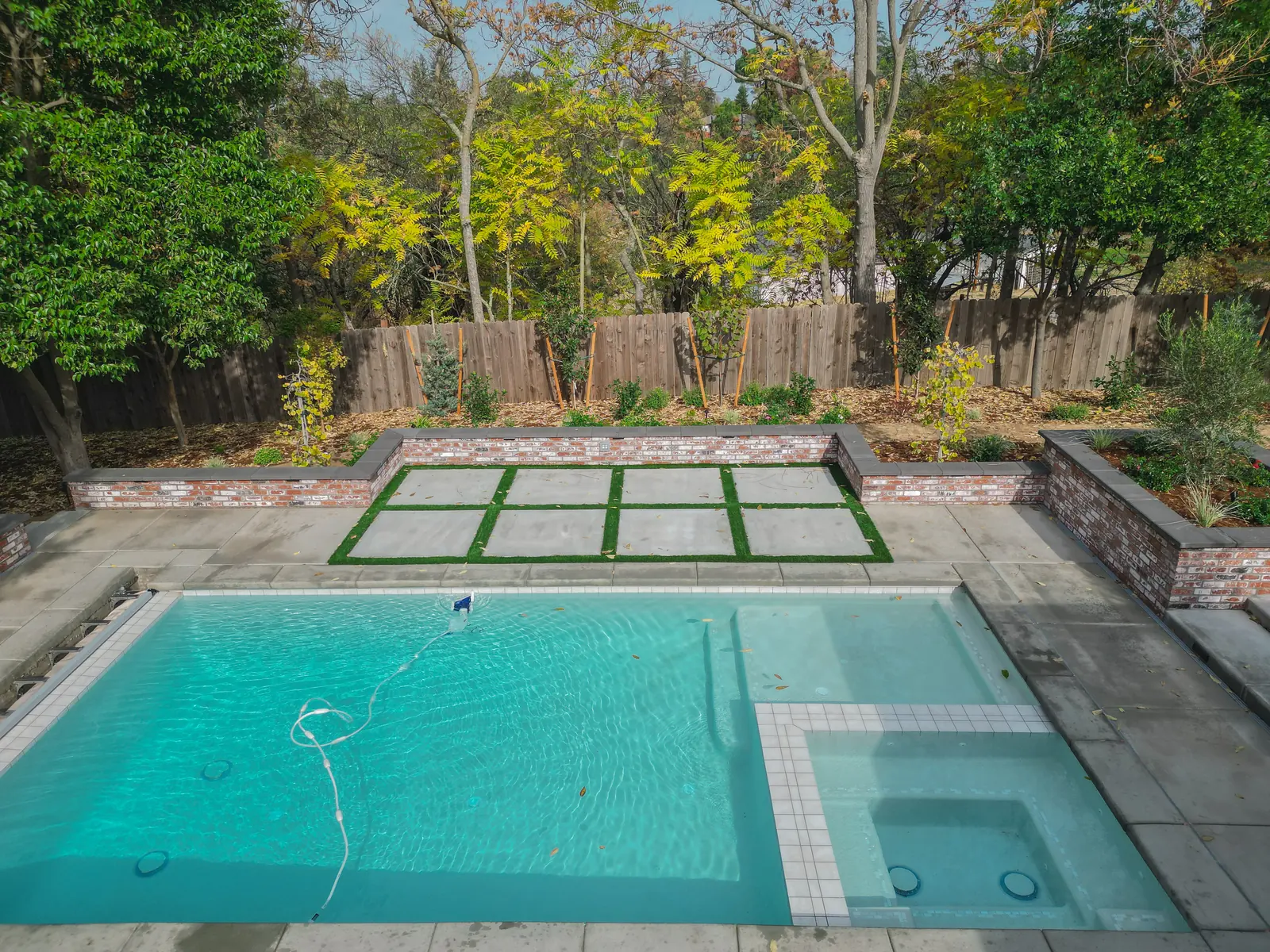 Backyard with concrete pavers in a turf grid, planting beds, and a pool in Sacramento